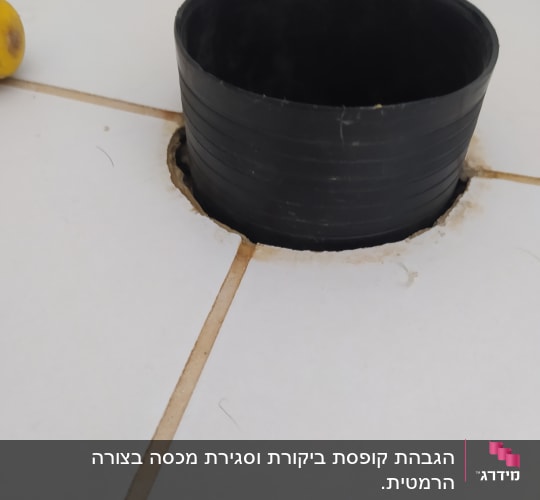 צינור שחור עגול בתוך חור ברצפה לבנה